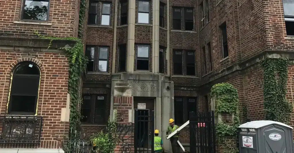 Construction workers renovating a historic brick apartment building in Philadelphia, with ivy on the walls.