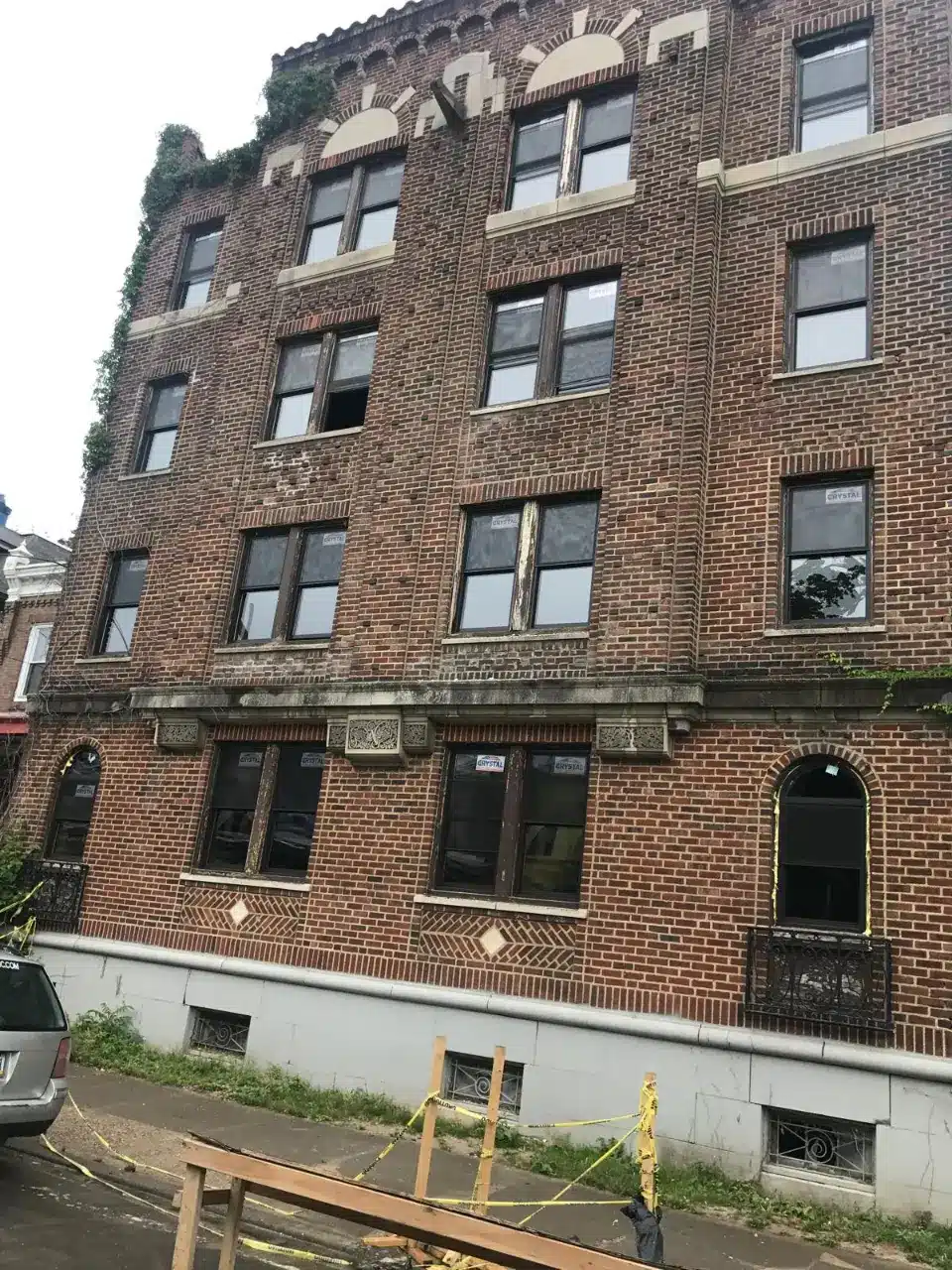 Four-story red brick apartment building with new window installations managed by Realty Management Services.