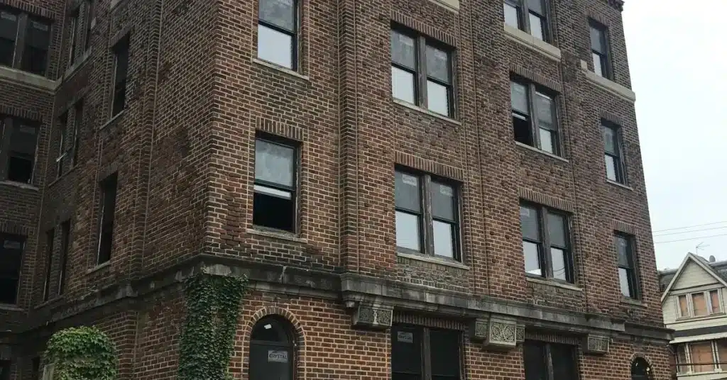 Brick apartment building with multiple windows and ivy on the lower wall, representing a typical structure needing rental property insurance.